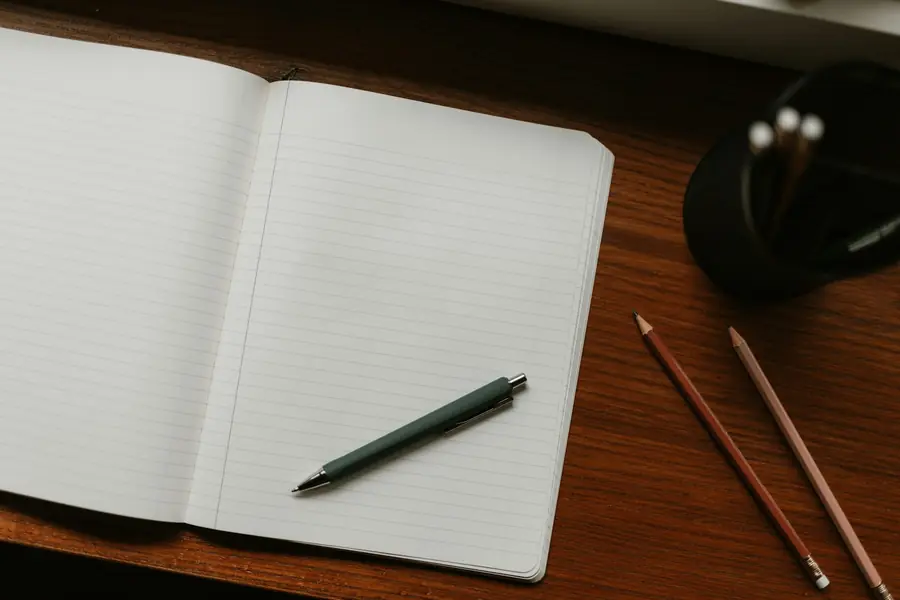 Buku catatan terbuka dengan pena dan pensil di atas meja